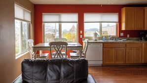 Una cocina con armarios de madera, un lavavajillas blanco y una ventana con vistas a un edificio.