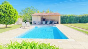 Una piscina amb gandules, zona de barbacoa i jardí.