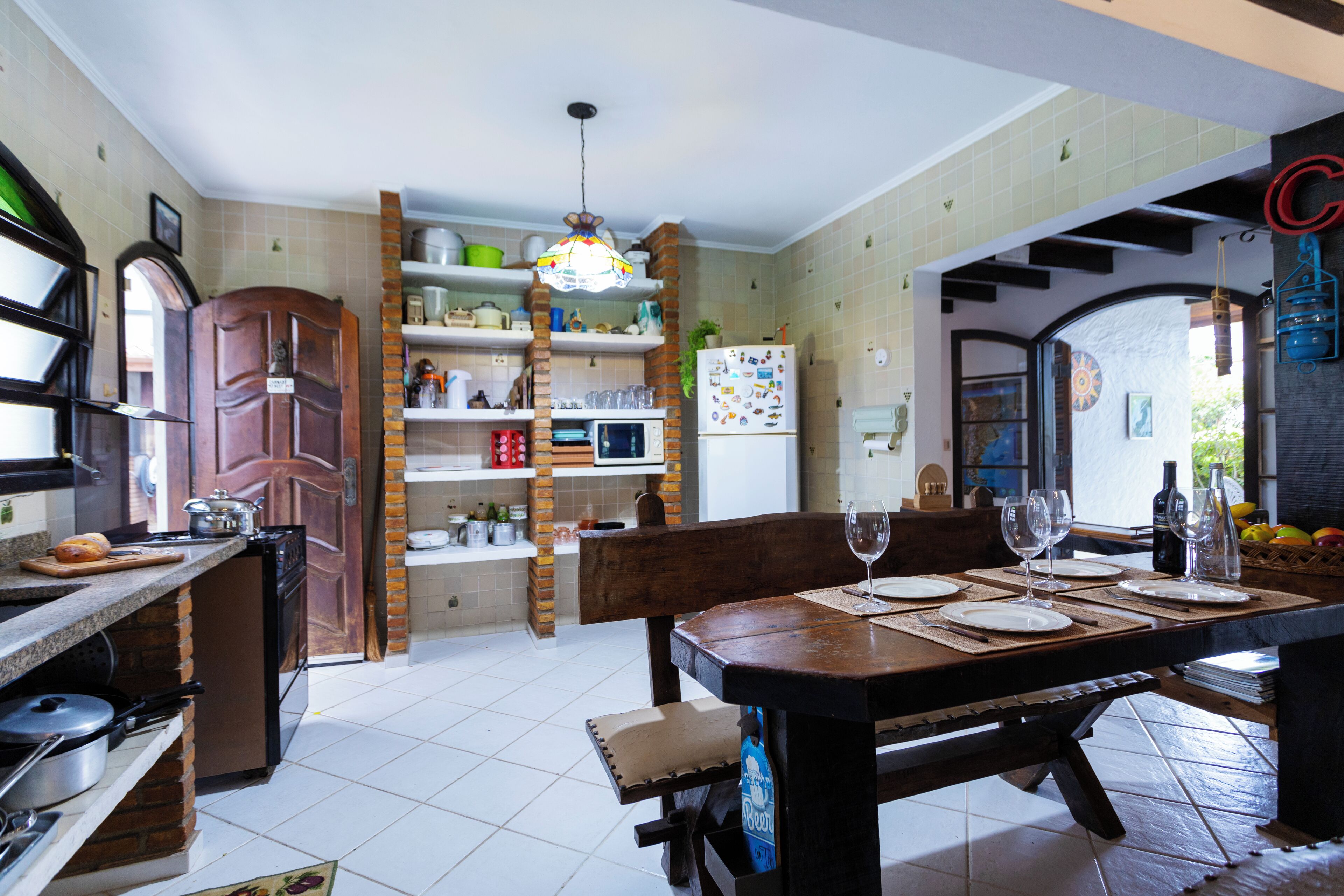A kitchen with a dining table set for four, a refrigerator, and various kitchen appliances.