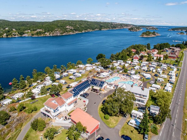 An aerial view of a campground with RVs, a swimming pool, and a large building with solar panels. - 11 Person Holiday Home in Risor (Risør)