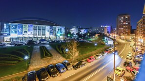 A nighttime view of a cityscape with a large illuminated building, a parking lot with cars, and surrounding urban buildings. - Elegance Studio - Cismigiu Gardens - Free Wifi - Panoramic View (București)