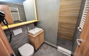 A modern bathroom with a wooden vanity, white sink, and toilet.