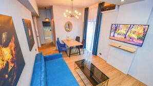 Een moderne woonkamer met een bank, salontafel en televisie. Er is een eethoek met stoelen en een tafel.