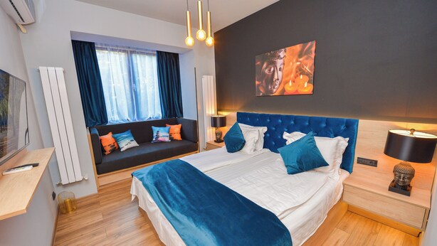 Een moderne slaapkamer met een groot bed, een bank en een raam met gordijnen.