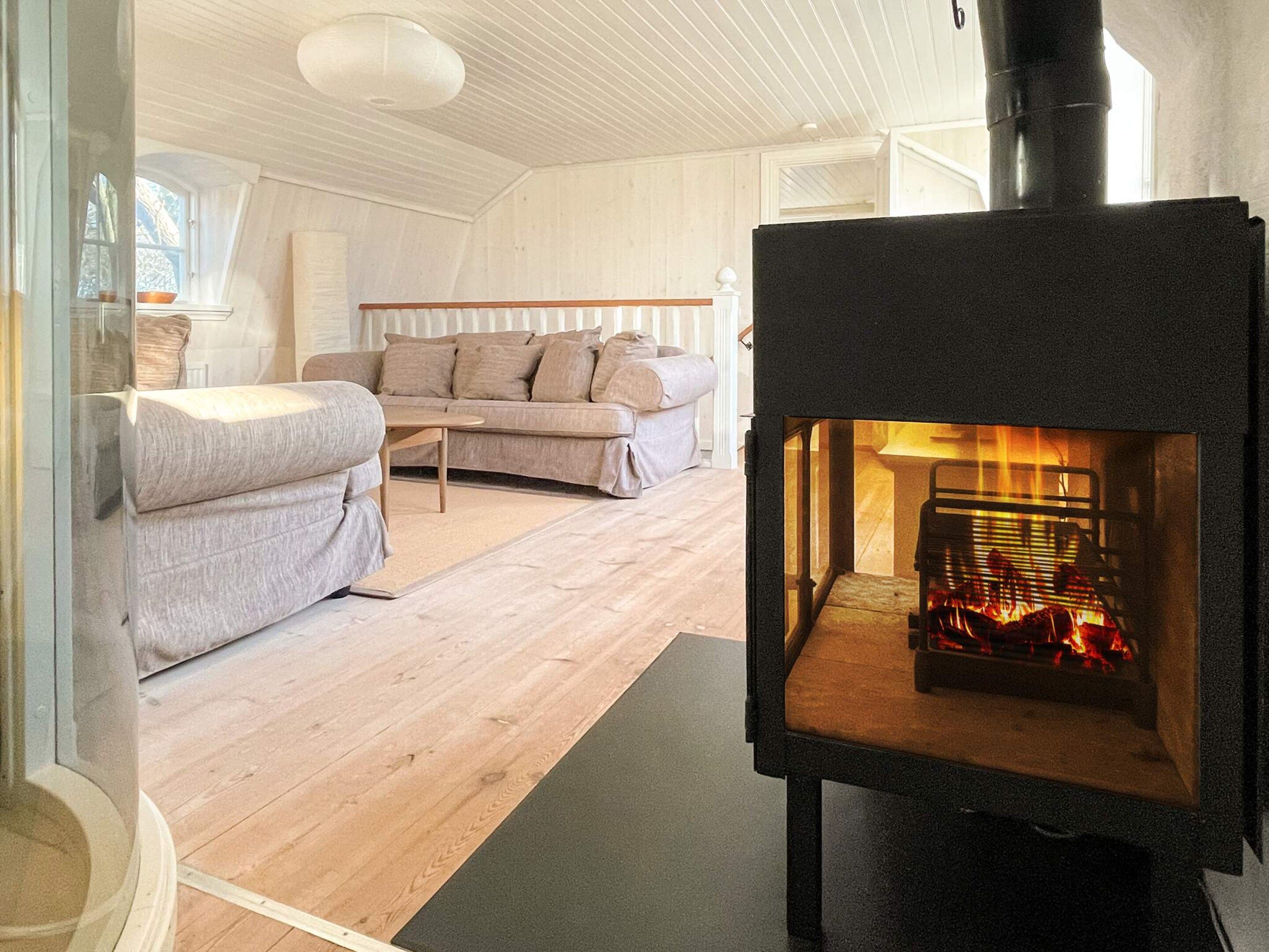 A cozy living room with a modern sofa, a small table, and a wood-burning stove.