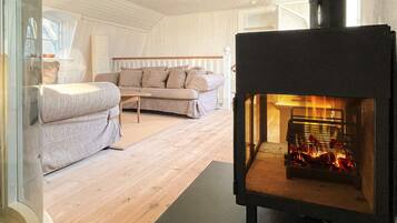 A cozy living room with a modern sofa, a small table, and a wood-burning stove.