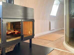 A modern wood-burning stove in a room with wooden flooring and a sloped ceiling. - 4 Star Holiday Home in Farjestaden (Farjestaden)