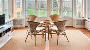 A dining area with wicker chairs, a glass table, and a view of the outdoors through large windows. - 4 Star Holiday Home in Farjestaden (Farjestaden)