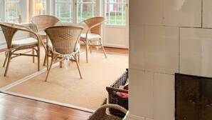 A room with wicker chairs, a fireplace, and large windows. - 4 Star Holiday Home in Farjestaden (Farjestaden)
