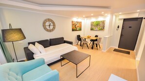A modern living room with a sofa, a coffee table, a dining table with chairs, a clock, and artwork on the walls.