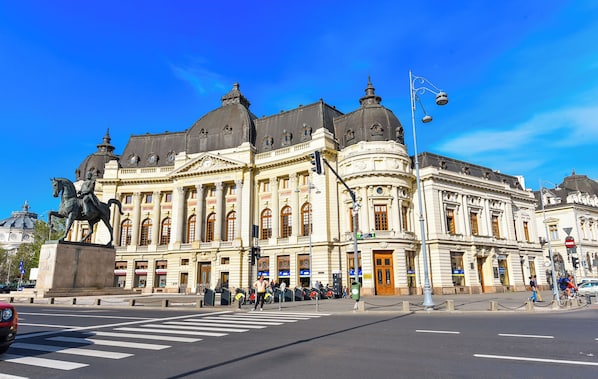 A historic building with classical architecture, large windows, and a prominent statue.