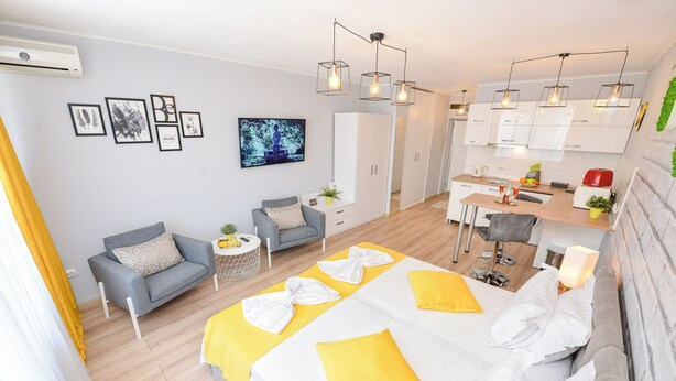 A modern hotel room with a bed, a sofa, a dining area, and a kitchen. - Candy Studio - Cismigiu Gardens - Quiet Room - Open Kitchen -Smart Tv (București)