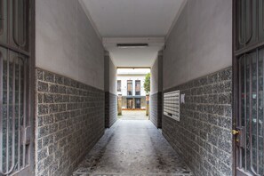 A narrow hallway with tiled walls and a tiled floor, leading to a building entrance. - Naitly Milano Dergano (Milan)