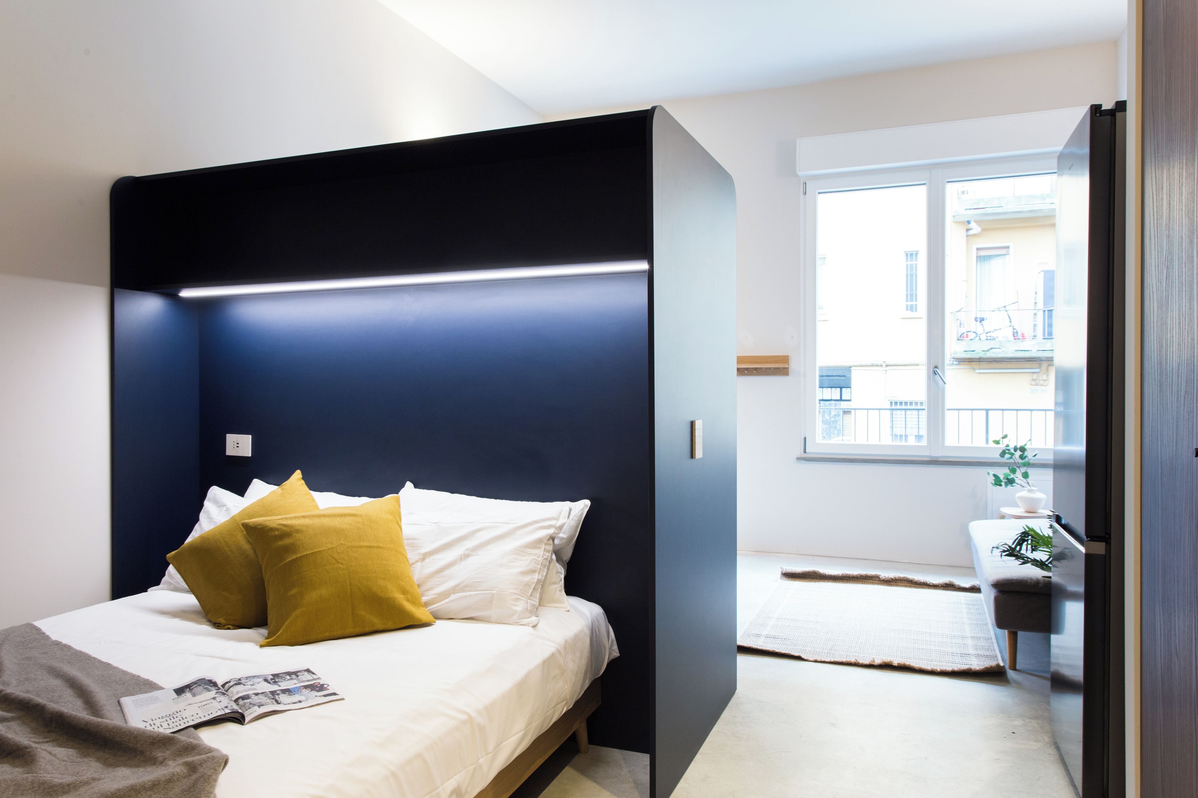 Una camera da letto moderna con un letto, un comodino e una finestra vista edifici.