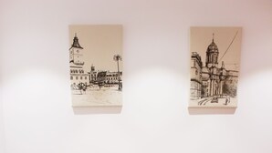 Une table à manger recouverte d’une nappe, avec des chaises rouges et deux dessins en noir et blanc accrochés au mur.