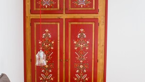 Une pièce avec une armoire en bois, un luminaire suspendu et plusieurs coussins.