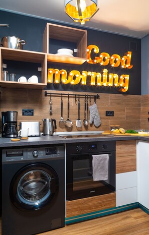 A modern kitchen with a washing machine, oven, and a 'Good morning' sign.