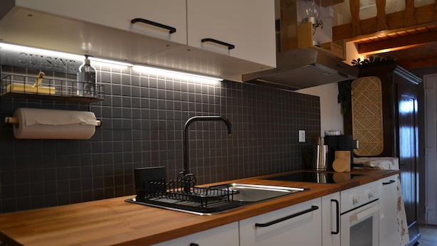 Una cocina moderna con encimera de madera, pileta de acero inoxidable y horno empotrado.