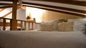 Un dormitorio con techo de madera y una cama con ropa de cama blanca y almohadas a rayas.