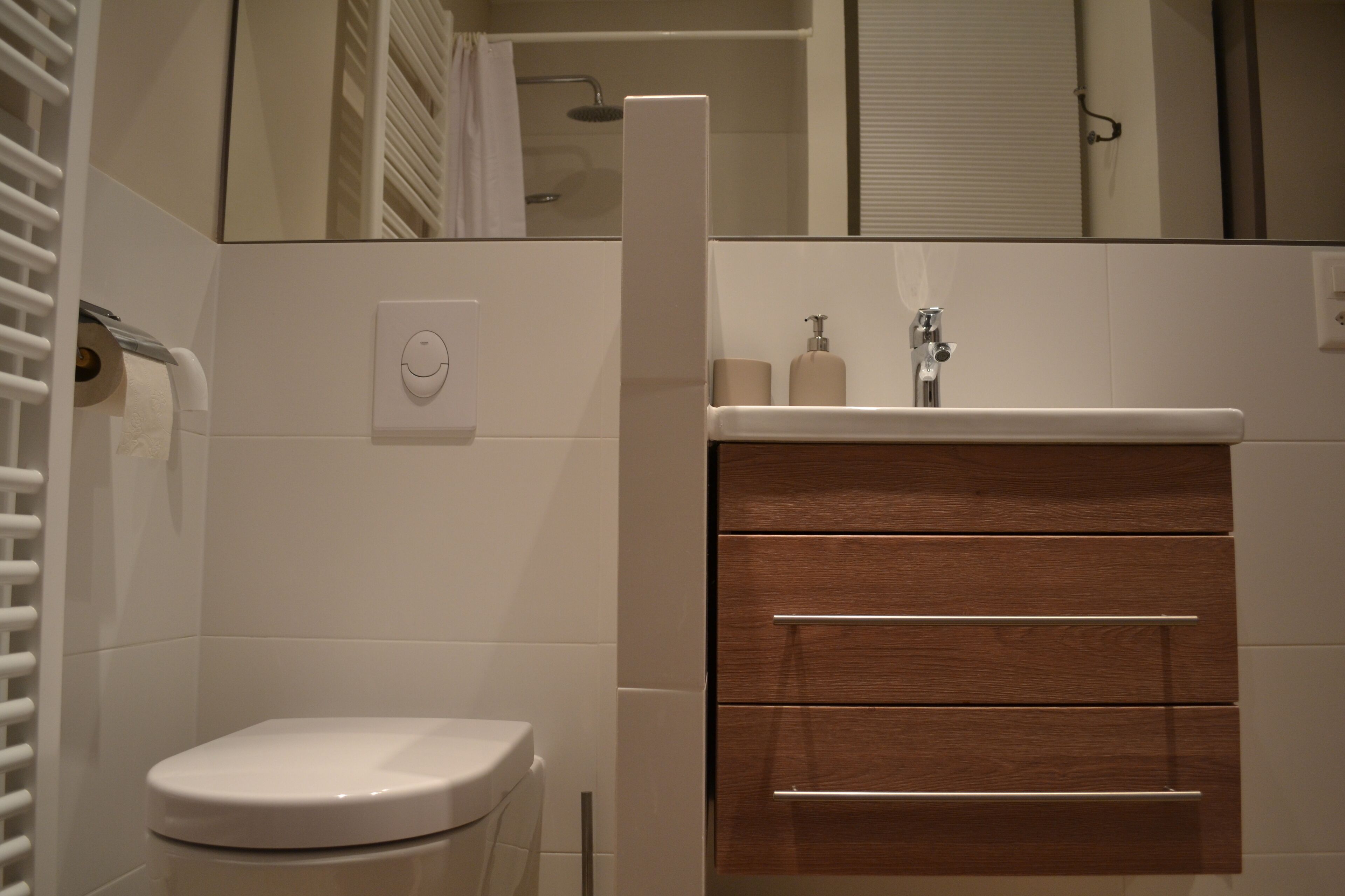 Une salle de bain moderne comprenant des toilettes, un meuble-lavabo avec un miroir et un espace douche.