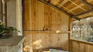 Una cabaña de madera con una cama individual, una silla de madera, una estantería con un adorno y una planta en maceta.