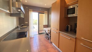 A compact kitchen with a stove, microwave, and modern cabinetry. - Albufeira Sunny Style by Homing (Albufeira)