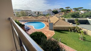 A rooftop swimming pool with lounge chairs, surrounded by greenery and buildings. - Albufeira Sunny Style by Homing (Albufeira)