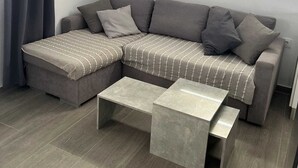 A modern living room with a sectional sofa, a small coffee table, and a wall-mounted air conditioner. - Terapia Salada I   . (Zahora)