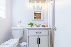 Ein Badezimmer mit Toilette, Waschbecken, Spiegel und Schränken.