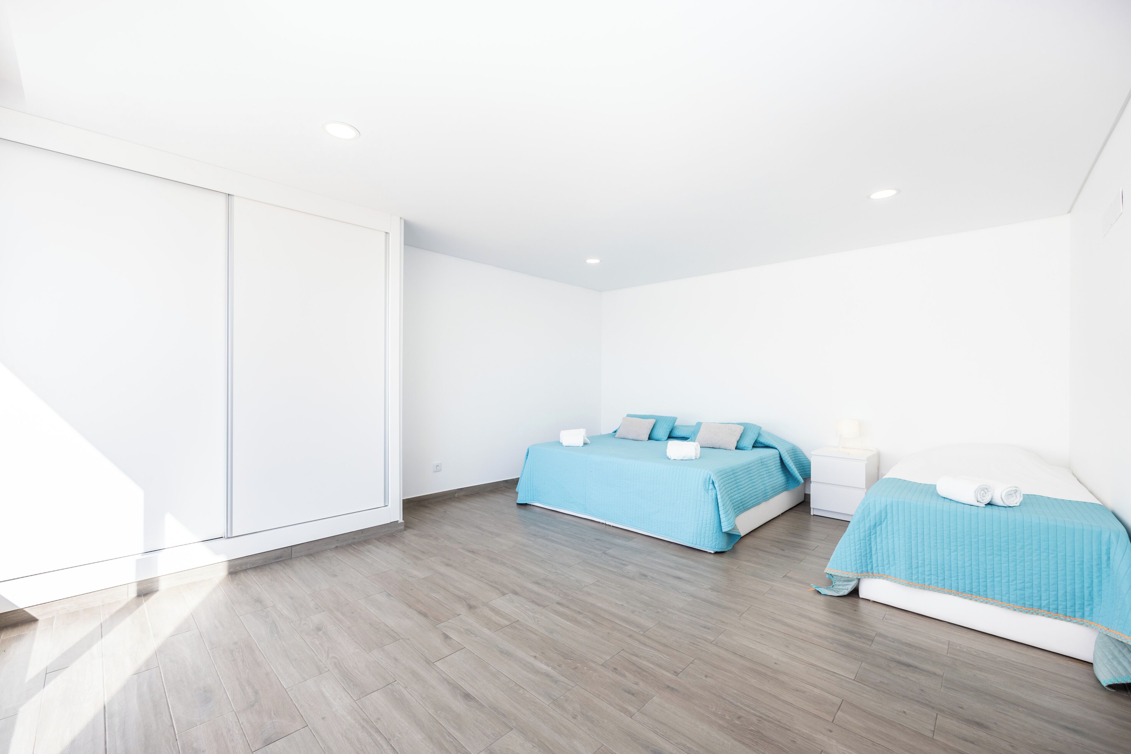 Une chambre moderne avec deux lits, une armoire et une table de chevet.