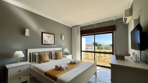A hotel room with a bed, bedside tables, a TV, and a balcony with a view. - Albufeira Central 8 by Homing (Albufeira)
