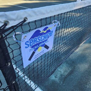 Un terrain de tennis avec un filet et une pancarte indiquant « Seascape Pickleball », situé à Miramar Beach, en Floride.