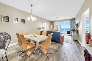 Una habitación de hotel moderna con zona de comedor, televisor y balcón con vistas.