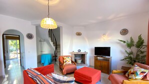 Una sala de estar con sofá, reposapiés y sillones, televisión y chimenea.