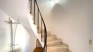 Una escalera con detalles de mármol, una silla de madera y una silla azul.