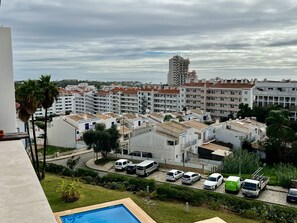 Ett bostadsområde med flera vita hyreshus, en swimmingpool och parkerade fordon.