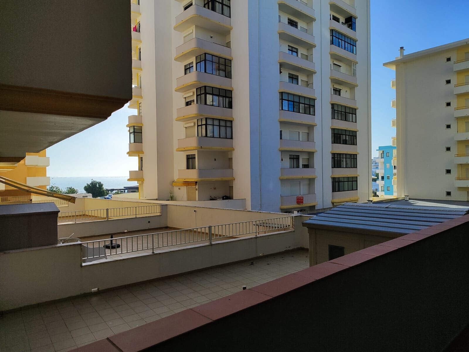 A high-rise residential building with multiple balconies and a view of the sea.