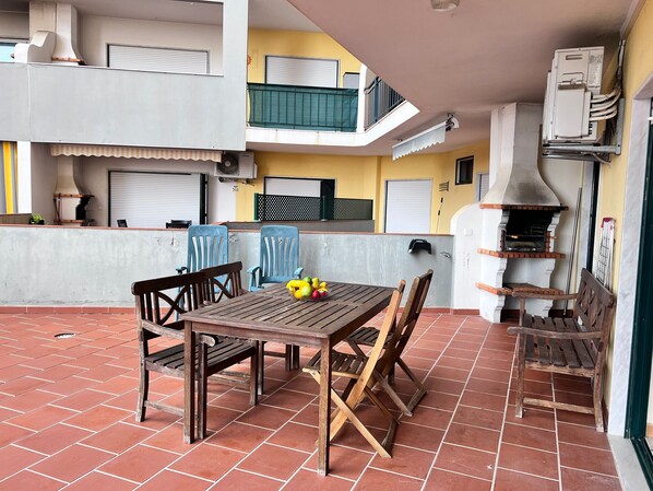 An outdoor patio with a wooden table and chairs, a small grill, and a tiled floor. - Armação DE Pêra Ocean Terrace by Homing (Silves)