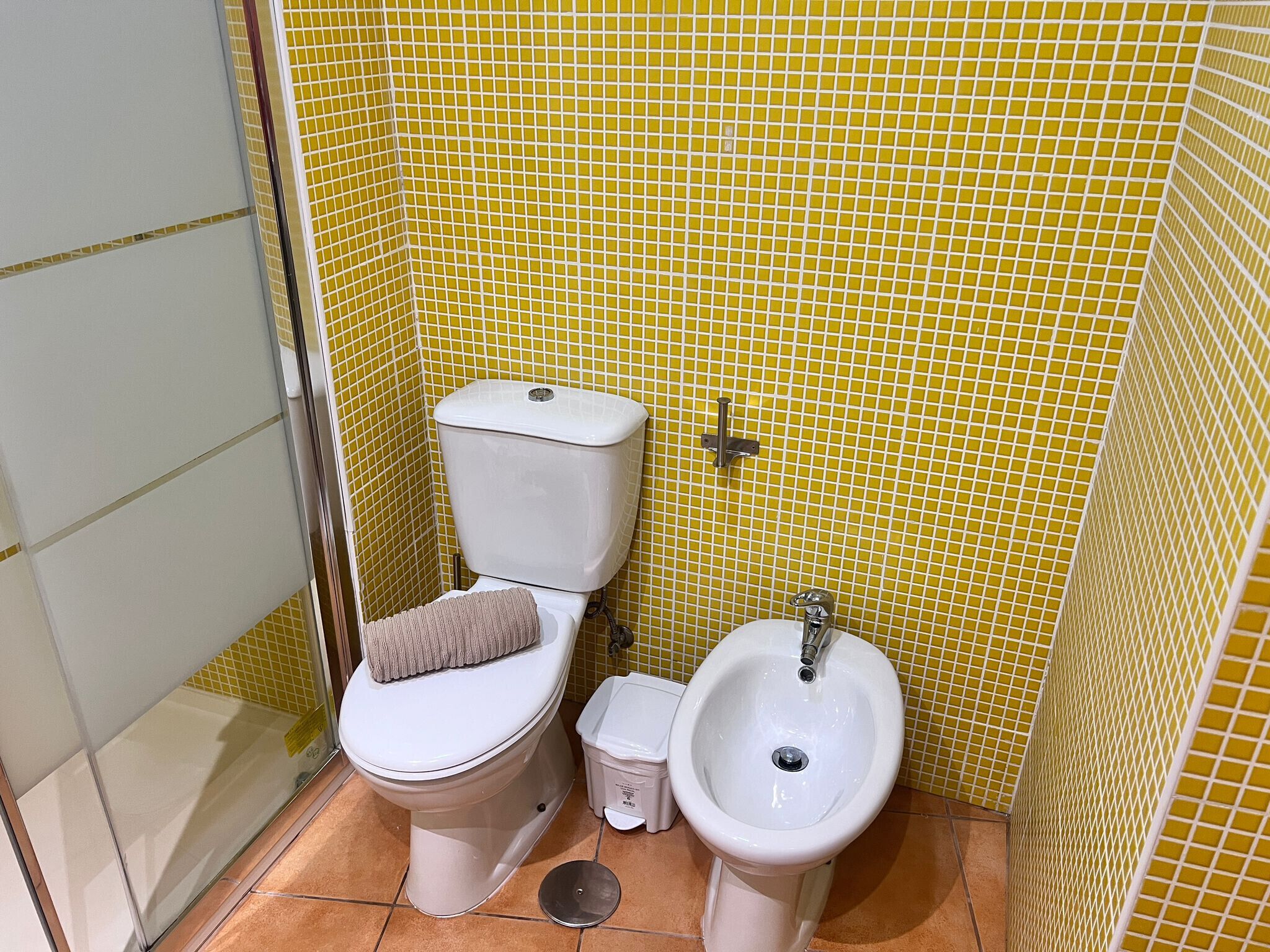 A small bathroom with a toilet, bidet, and tiled walls.
