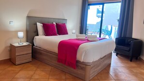 A hotel room with a bed, nightstands, a chair, and a view of the outside. - Armação DE Pêra Ocean Terrace by Homing (Silves)