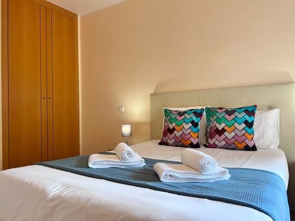 A hotel room with a bed, two pillows, a nightstand, and a wooden wardrobe. - Armação DE Pêra Ocean Terrace by Homing (Silves)