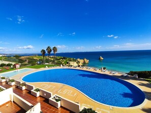 A large, curved swimming pool with a clear view of the ocean and rocky coastline in the background. - Lagos Ocean BAY With Pool by Homing (Lagos)