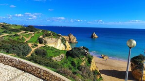 A coastal landscape with rocky cliffs, a sandy beach, and a clear blue sky. - Lagos Ocean BAY With Pool by Homing (Lagos)
