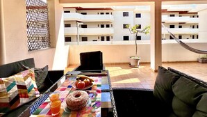A balcony with a table set for breakfast, a hammock, and a potted plant. - Lagos Ocean BAY With Pool by Homing (Lagos)