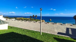 A rooftop terrace with a clear view of the sea, palm trees, and a spherical light fixture. - Lagos Ocean BAY With Pool by Homing (Lagos)