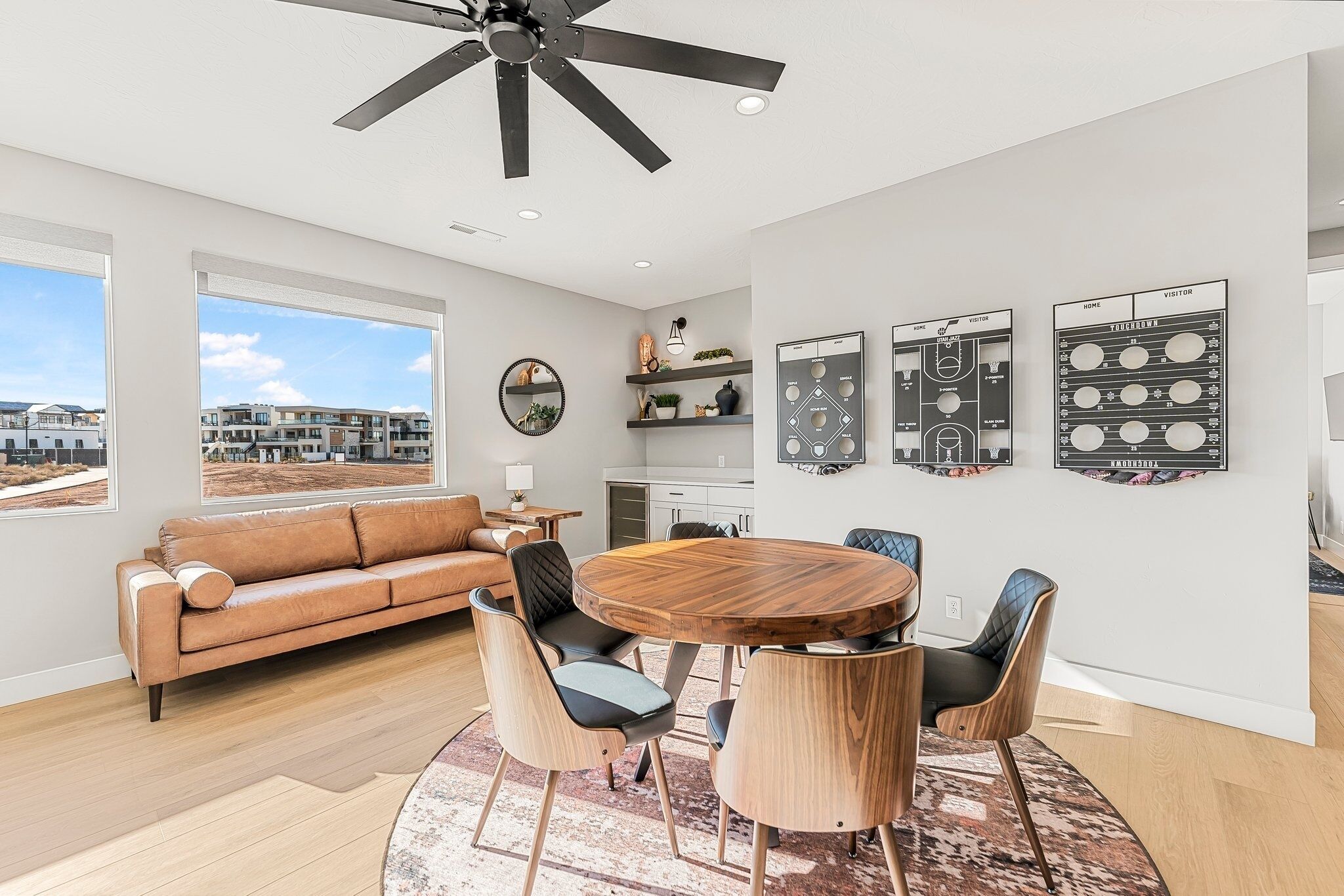 A modern living room with a round wooden table, leather sofa, and a city view.