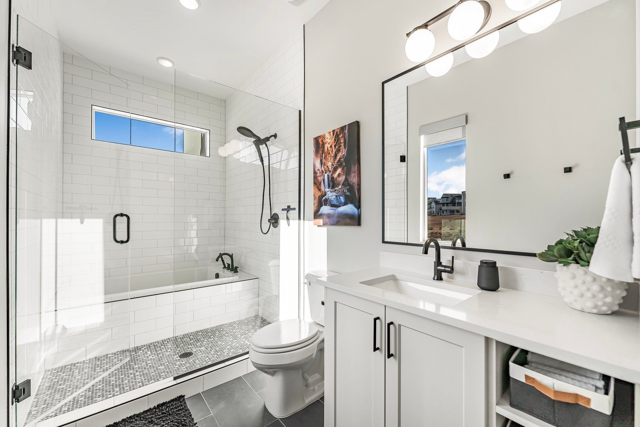 A modern bathroom with a glass-enclosed shower, a white sink, and a large mirror.