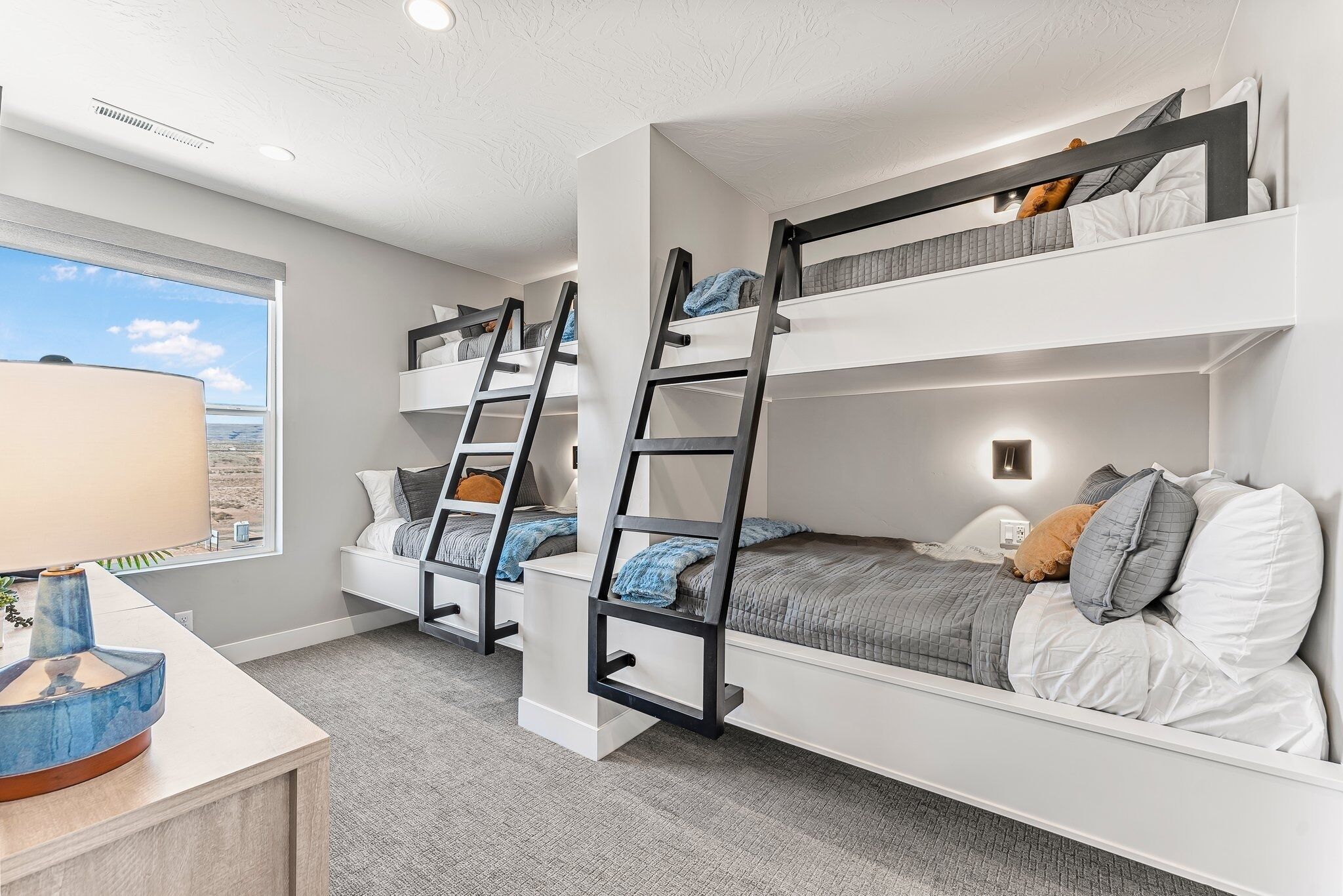 Ein Zimmer mit Etagenbetten, einem Schreibtisch mit Lampe und einem Fenster mit Blick.