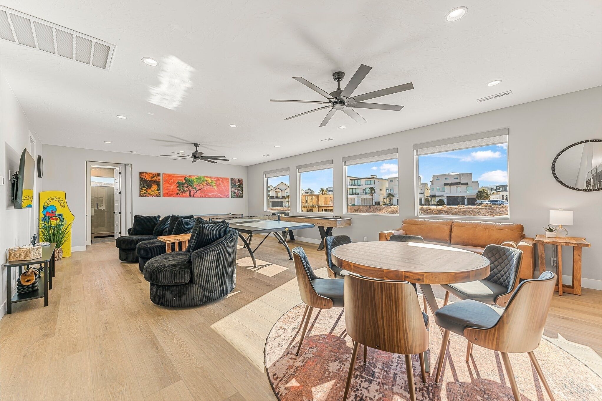 A spacious living area with a dining table, sofas, and a ceiling fan.