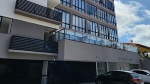 Een meerlaags gebouw met een modern architectonisch ontwerp, voorzien van balkons met metalen leuningen en grote ramen.